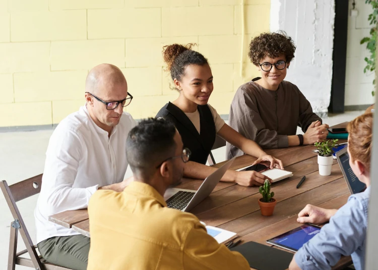 Five people sat around a table having a meeting
